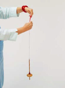 person drafting fibers with a drop spindle